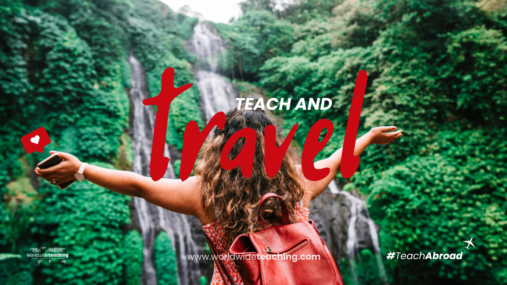 A young traveller spreads her arms in awe of the idyllic scene before her: a waterfall surrounded by trees in a clearing of a tropical rainforest.